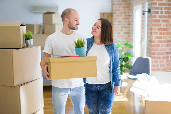 Jong paar verhuizen naar een nieuw huis, glimlachend gelukkig houden cardboa — Stockfoto