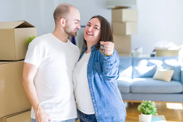 Junges Paar lächelt sehr glücklich und zeigt Schlüssel der neuen Heimat, zieht um — Stockfoto