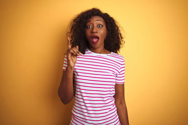 縞模様のTシャツを着た若いアフリカ系アメリカ人女性は 黄色の背景を独立したアイデアで指差している 興奮し 第一番 — ストック写真