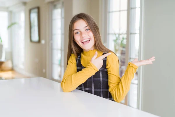 Hermosa Niña Joven Sentada Mesa Sorprendida Sonriendo Cámara Mientras Presenta — Foto de Stock