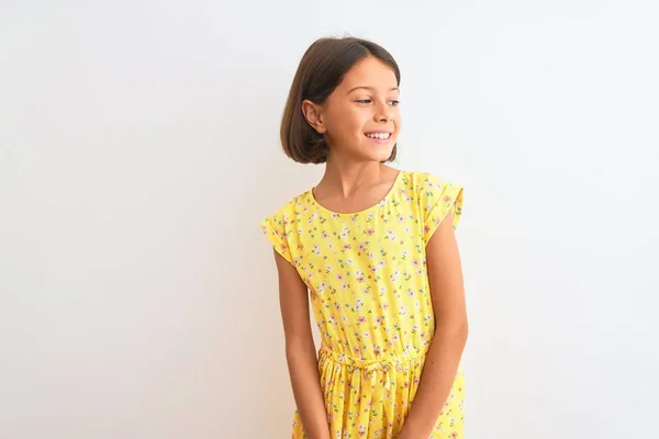 年轻美丽的小女孩穿着黄色的花裙子 站在孤零零的白色背景上 面带微笑地看着旁边 自然的表情 充满自信的笑 — 图库照片
