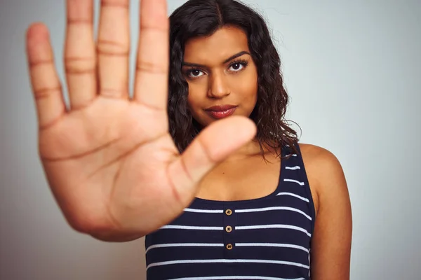 Beautiful transsexual transgender woman wearing striped t-shirt over isolated white background with open hand doing stop sign with serious and confident expression, defense gesture