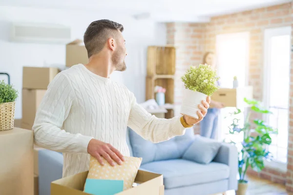 Pareja joven mudándose a un nuevo hogar, hombre guapo sonriendo c — Foto de Stock