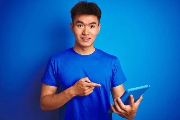 年轻的亚裔男子用石碑站在孤立的蓝色背景上 非常高兴地用手和手指指指点点 — 图库照片