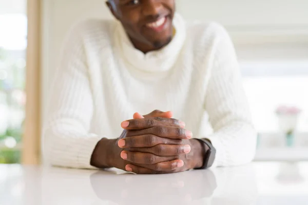 Close up de mãos cruzadas do homem africano sobre a mesa sorrindo — Fotografia de Stock