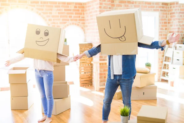 Pár zábavy v novém bytě nosí krabice se směšnou tváří — Stock fotografie