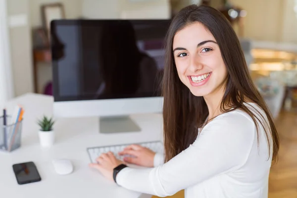 Jovem sorrindo trabalhando usando o computador e mostrando um branco s — Fotografia de Stock