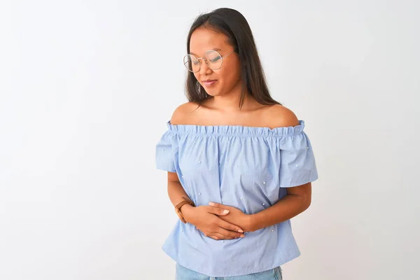 年轻的中国女人穿着蓝色的T恤 戴着眼镜 双手放在胃部的白色背景上 因为恶心 痛苦的疾病感觉不舒服 阿切概念 — 图库照片