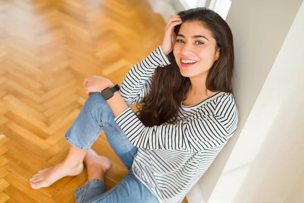 Güzel esmer kadın büyük bir gülümseme ile neşeli gülümseyen, pozitif ve mutlu yerde oturan bakıyor