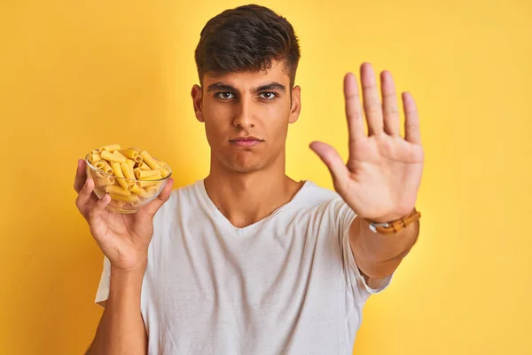 Young Indian Man Holding Bowl Dry Pasta Standing Isolated Yellow — Stock Photo, Image