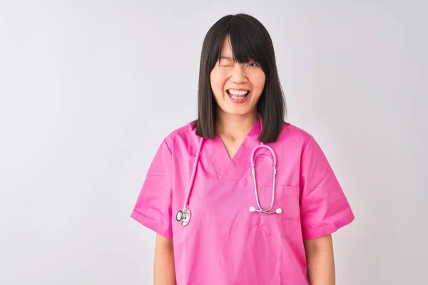 年轻美丽的中国护士 戴着听诊器 站在孤独的白色背景上 眨着眼睛 带着性感的表情 开朗而快乐地看着摄像机 — 图库照片