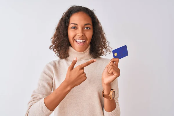 若いですブラジル人女性保持クレジットカードスタンディング上の隔離された白い背景非常に幸せなポインティングとともに手と指 — ストック写真