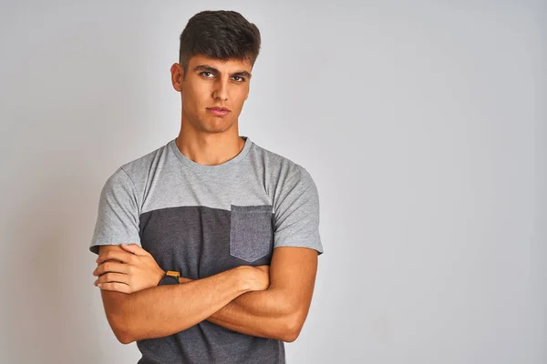 Young indian man wearing casual t-shirt standing over isolated white background skeptic and nervous, disapproving expression on face with crossed arms. Negative person.