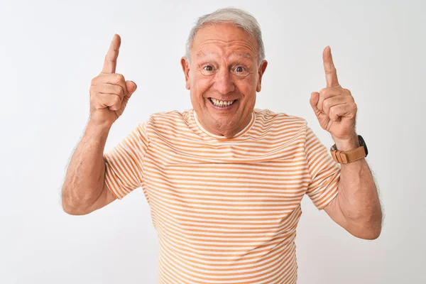 İzole edilmiş beyaz arka planda duran çizgili tişört giyen yaşlı gri saçlı adam şaşırmış, şaşırmış ve parmaklarıyla işaret ediyor ve kollarını kaldırıyordu..