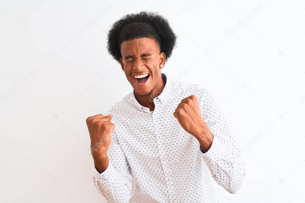 Young african american man wearing elegant shirt standing over isolated white background very happy and excited doing winner gesture with arms raised, smiling and screaming for success. Celebration concept.