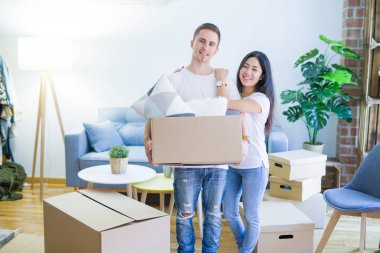 Young beautiful couple sitting on the floor at new home around cardboard boxes skeptic and nervous, disapproving expression on face with crossed arms. Negative person.