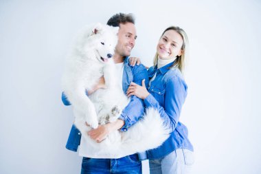 Genç güzel çift izole beyaz arka plan üzerinde duran köpek tutarak