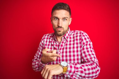 Genç ve yakışıklı bir adam kırmızı arka planda kaldı. Aceleyle zamanı, sabırsızlığı ve gecikmeyi gösteriyor.