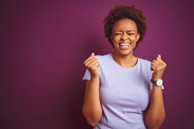 Güzel Afro saçlı, siyah saçlı, genç, güzel bir Afro Amerikalı kadın. Başarılı olmak için heyecanlı, kolları havada ve gözleri kapalı zaferi kutlarken gülümsüyor. Kazanan konsept.