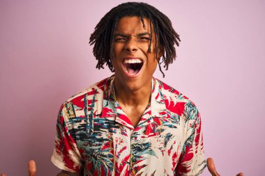 Tatilde rastalı bir afro adam çiçek desenli bir tişört giyiyor pembe arka planda başarının çılgınlığını kutluyor kolları havada ve gözleri kapalı heyecanla bağırıyor. Kazanan konsept