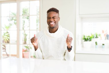 Beyaz masada yakışıklı Afrikalı Amerikan adam silah ile başarı için heyecanlı kutlamak zafer gülümseyen kaldırdı. Kazanan kavramı.