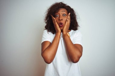 Genç Afro-Amerikalı kadın tişört giyiyor. İzole edilmiş beyaz arka planda duruyor. Korkuyor ve şokta.