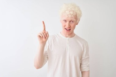 Sıradan tişörtler giyen genç albino sarışın adam izole edilmiş beyaz arka planda durup başarılı bir fikri işaret ediyor. Heyecanlı ve mutlu. Bir numara..