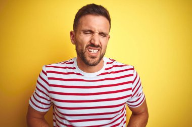 Genç, yakışıklı bir adam sarı renkli tişört giyer midenin üstünde el ele tutuşur çünkü hazımsızlık, acı veren bir hastalık yüzünden kendini kötü hisseder. Ache kavramı.