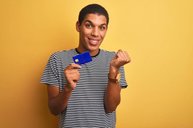 Sarı arka planda duran genç, yakışıklı Arap adam gururla bağırıyor ve zaferi ve başarıyı kutluyor. Çok heyecanlı, coşkulu bir duygu.