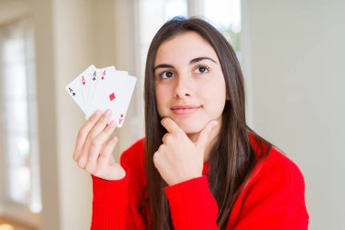 Beautiful young woman gambling playing poker serious face thinking about question, very confused idea