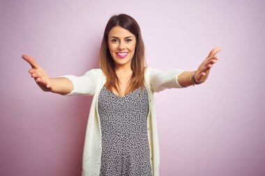 Pembe soyutlanmış arka planda duran genç ve güzel bir kadın gülümseyen, yardım eli uzatan ve kabullenen biri..