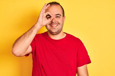 Kırmızı günlük tişört giyen genç adam izole edilmiş sarı arka planda gülümseyen bir yüzle duruyor.