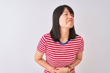 Genç, güzel Çinli bir kadın, izole edilmiş beyaz arka plan üzerinde kırmızı çizgili tişört giyiyor. Midenin üzerine el çökmüş. Çünkü hazımsızlık ve acı veren bir hastalık var. Ache kavramı.