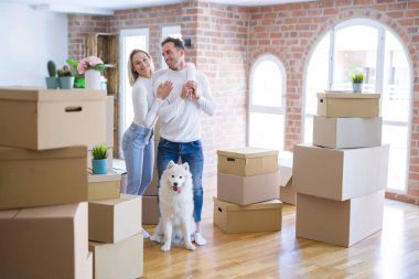 Karton kutular etrafında yeni evde duran köpek ile genç güzel çift