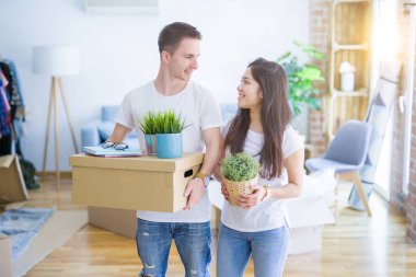 Young beautiful couple sitting on the floor at new home around cardboard boxes skeptic and nervous, disapproving expression on face with crossed arms. Negative person.