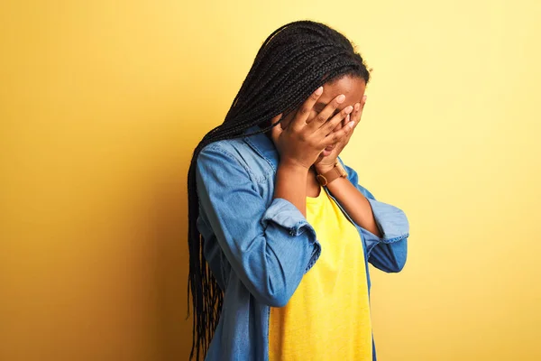 年轻的非洲裔美国女人穿着斜纹棉布衬衫 站在孤立的黄色背景上 脸上挂着忧郁的表情 一边哭一边用手捂住脸 抑郁症的概念 — 图库照片