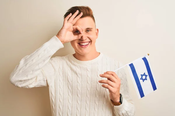 イスラエル国旗を手に持つ若いハンサムな男が白い背景の上に孤立し 幸せな顔は笑顔でOkサインをします — ストック写真