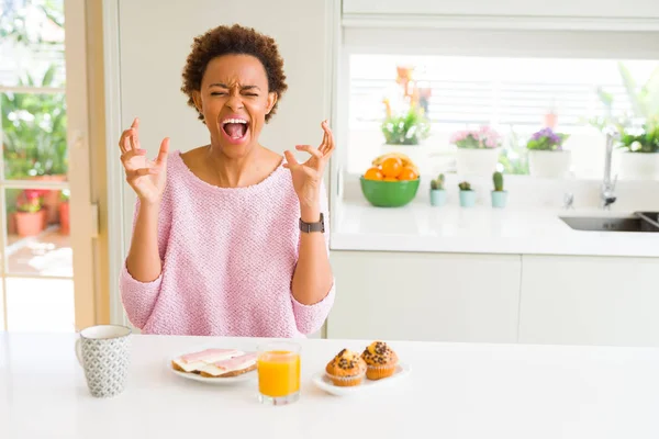 年轻的非洲裔美国女人早上在家里吃早餐庆祝疯狂和疯狂的成功 举起双臂 闭上眼睛尖叫着兴奋不已 赢的概念 — 图库照片