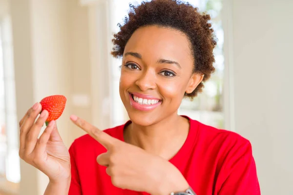 若いですアフリカ系アメリカ人女性食べる新鮮なイチゴのための朝食非常に幸せなポインティングとともに手と指 — ストック写真