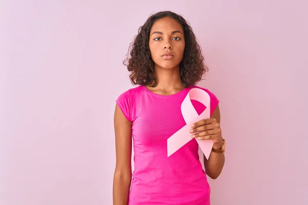 若いですブラジル人女性を保持癌リボン上に立って隔離されたピンクの背景とともに自信を持って式上のスマート顔の思考深刻な — ストック写真