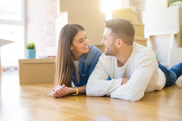 Junges schönes Paar, lächelnd auf dem Boden des neuen Hauses liegend — Stockfoto