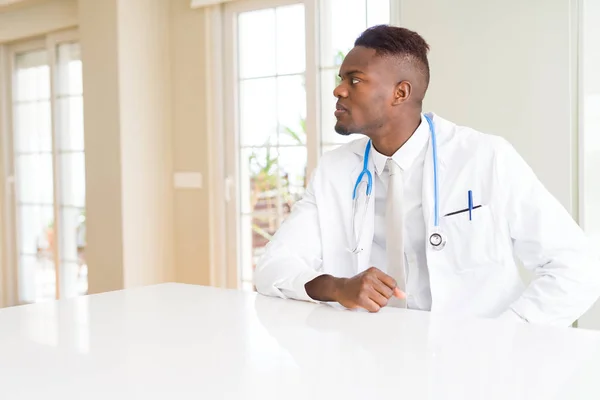 African american doctor man at the clinic looking to side, relax profile pose with natural face with confident smile.