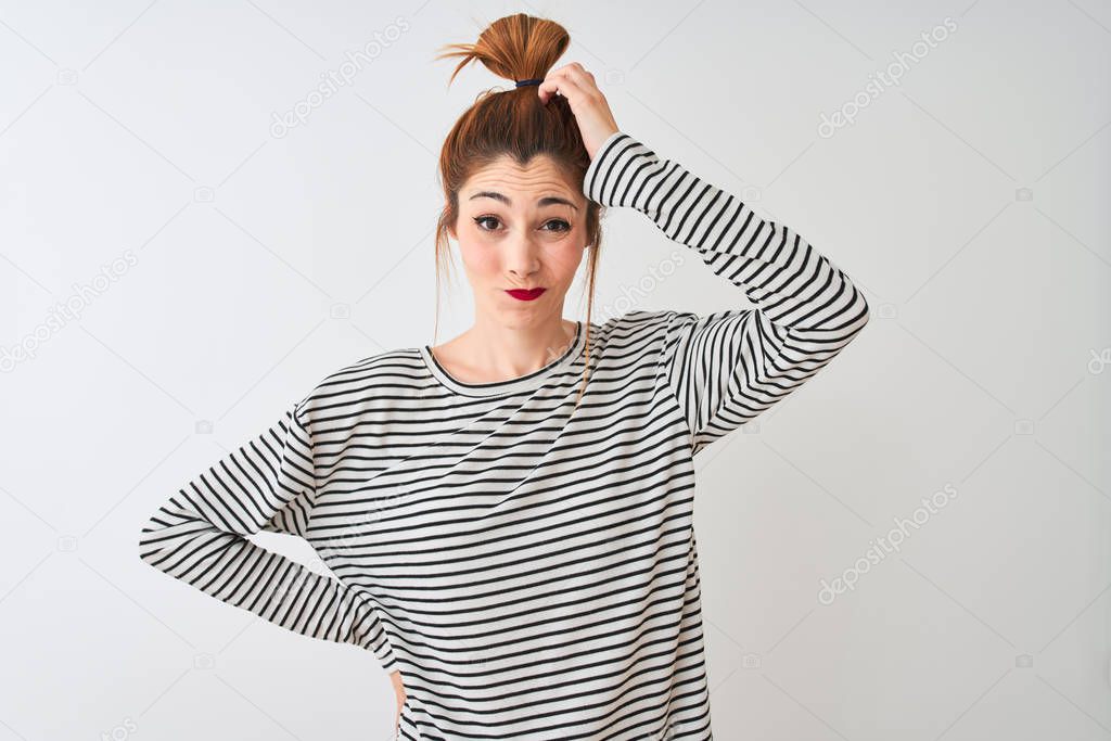 Redhead woman wearing navy striped t-shirt standing over isolated white background confuse and wonder about question. Uncertain with doubt, thinking with hand on head. Pensive concept.
