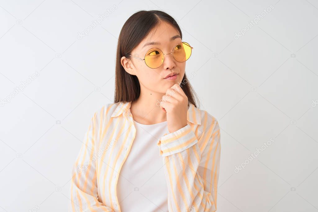 Young chinese woman wearing striped shirt and glasses over isolated white background serious face thinking about question, very confused idea