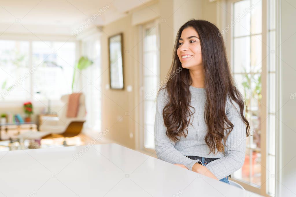 Young beautiful woman at home looking away to side with smile on face, natural expression. Laughing confident.