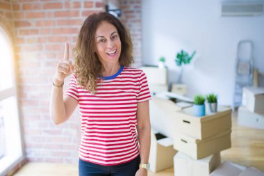 Orta yaşlı bir kadın yeni evine taşınıyor. Karton kutular paketleyip başarılı bir fikirle işaret ediyor. Heyecanlı ve mutlu. Bir numara..