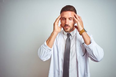 İzole edilmiş arka planda beyaz kürk giyen yakışıklı genç bir doktor. Stres yüzünden baş ağrısı çekiyor. Migren ağrısı..