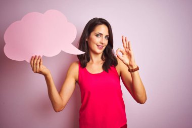 Pembe izole arka planda konuşma balonu tutan güzel bir kadın. Parmaklarıyla imza atıyor. Mükemmel bir sembol.