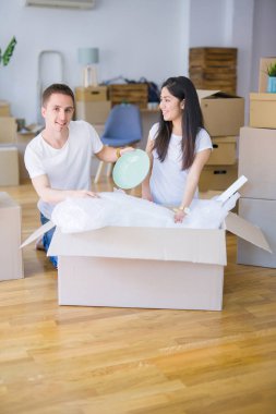 Young beautiful couple sitting on the floor at new home around cardboard boxes skeptic and nervous, disapproving expression on face with crossed arms. Negative person.