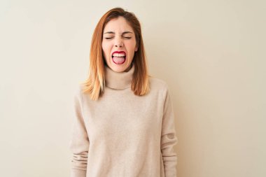 Redhead woman wearing elegant turtleneck sweater standing over isolated white background sticking tongue out happy with funny expression. Emotion concept.